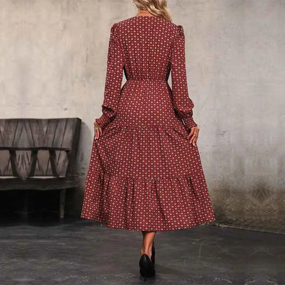 A woman wearing a long sleeve burgundy printed autumn dress with a subtle white geometric print and tiered skirt