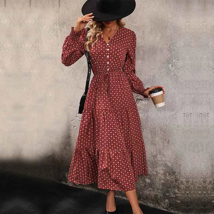A woman wearing a red long sleeve printed autumn dress with white floral patterns and a button-down front