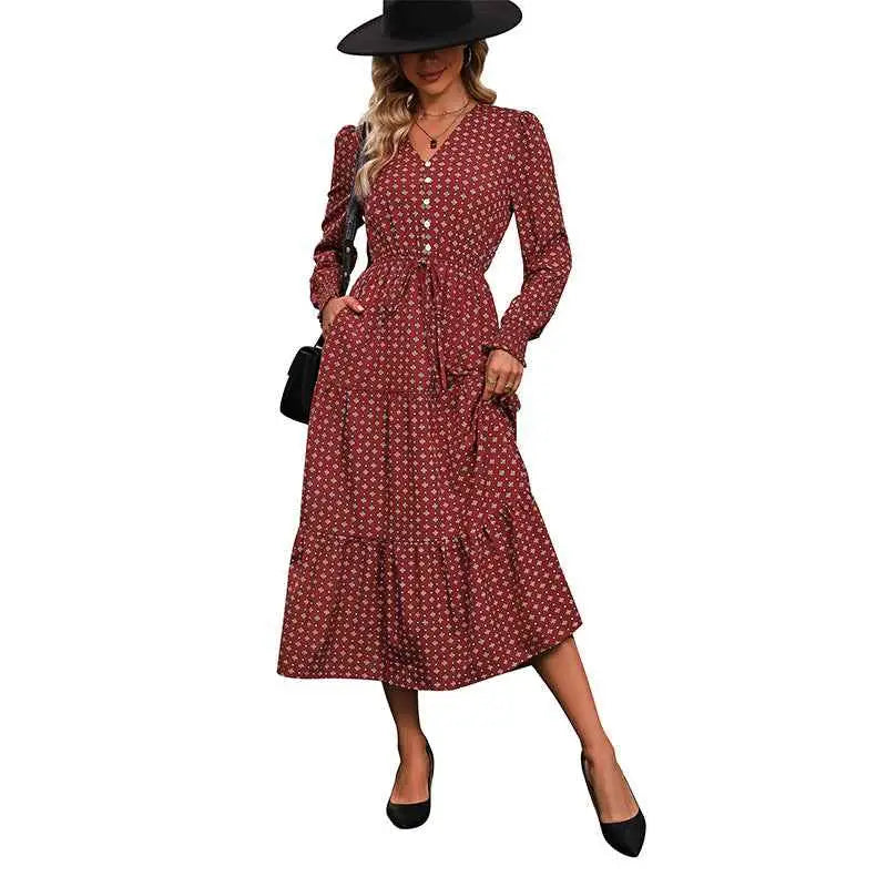 A woman wears a long sleeve printed autumn dress in deep red with white geometric patterns and a cinched waist